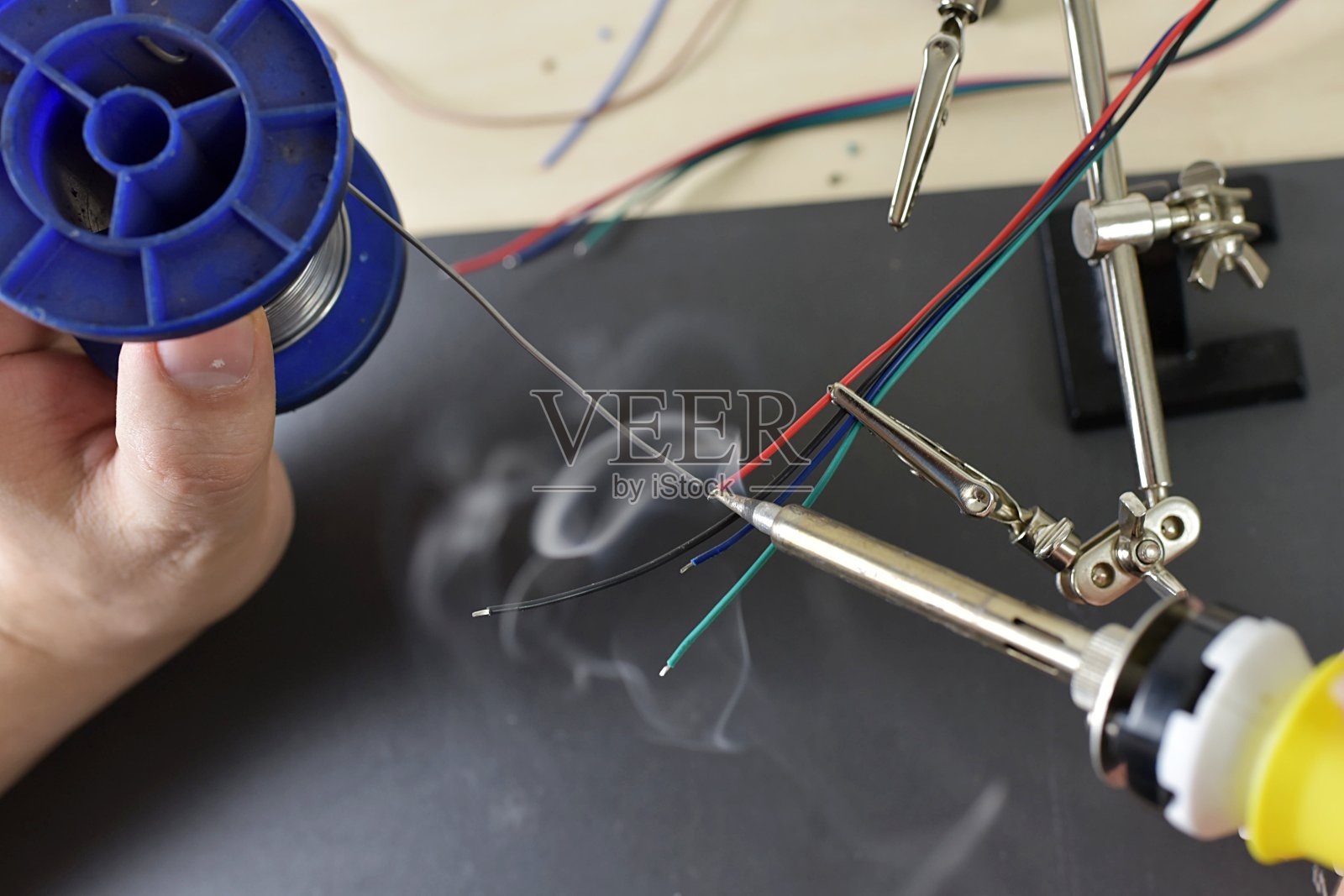 手拿烙铁和焊丝。连接在一起的电子部件照片摄影图片