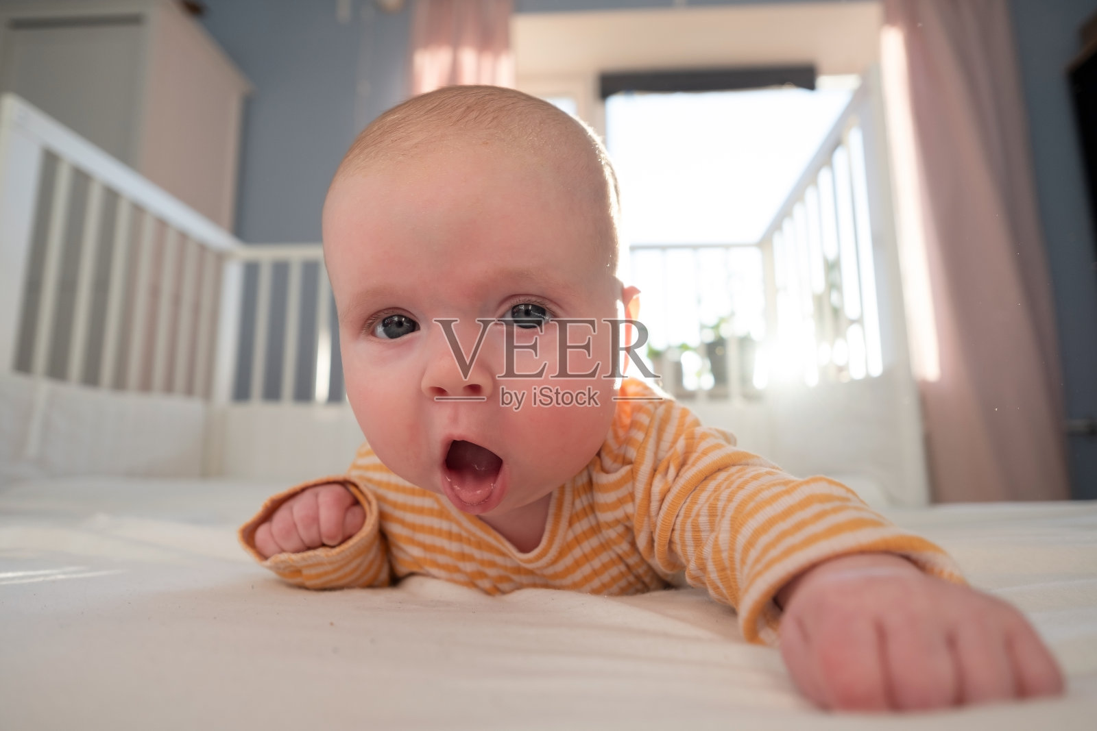 有趣的白人婴儿躺在床上。照片摄影图片