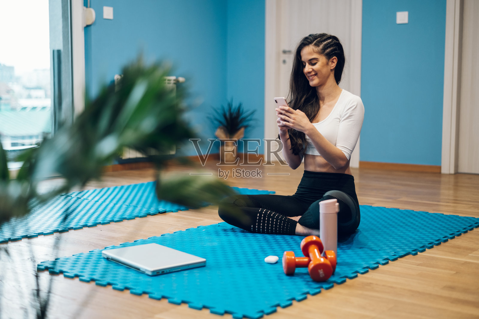 在家里训练时，一名女子在用她的智能手机微笑照片摄影图片