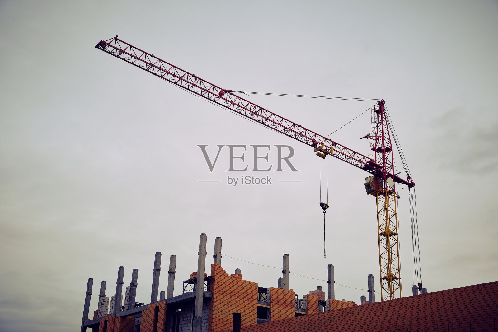 以高层建筑起重机为背景的一幢未完工的多层多层公寓住宅楼。照片摄影图片