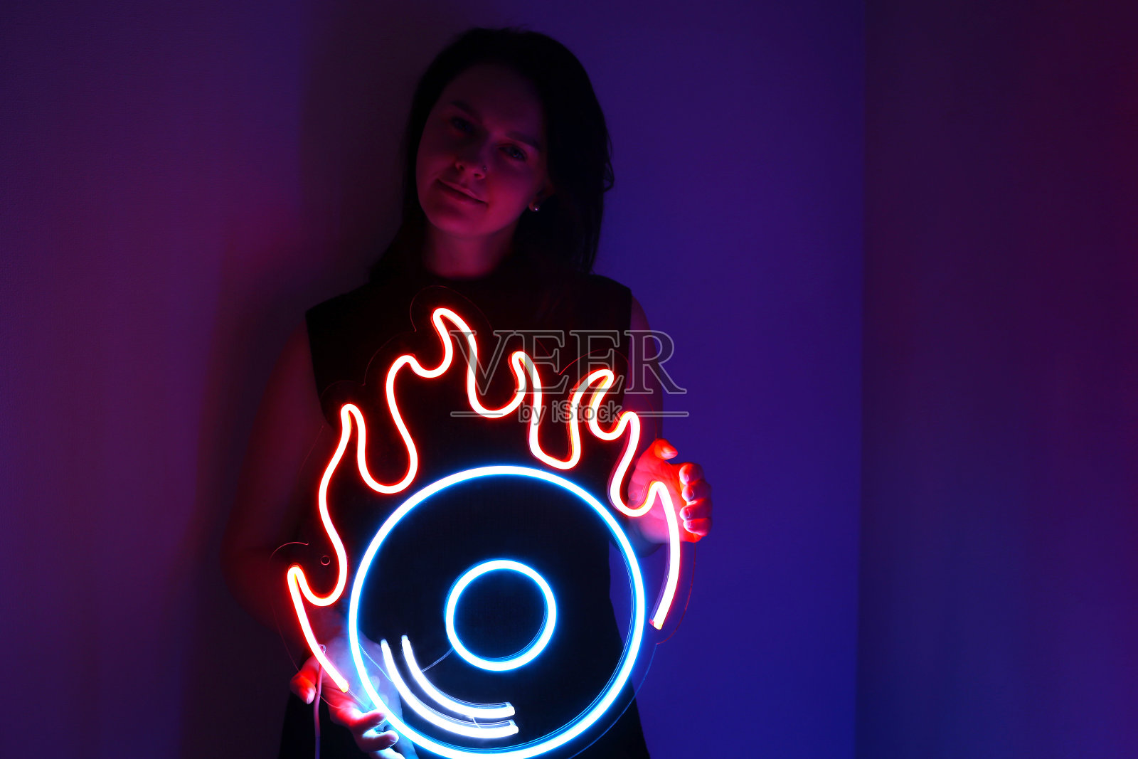 美丽的女孩和霓虹灯。橙色和蓝色的霓虹灯黑胶唱片。时尚的风格。照片摄影图片
