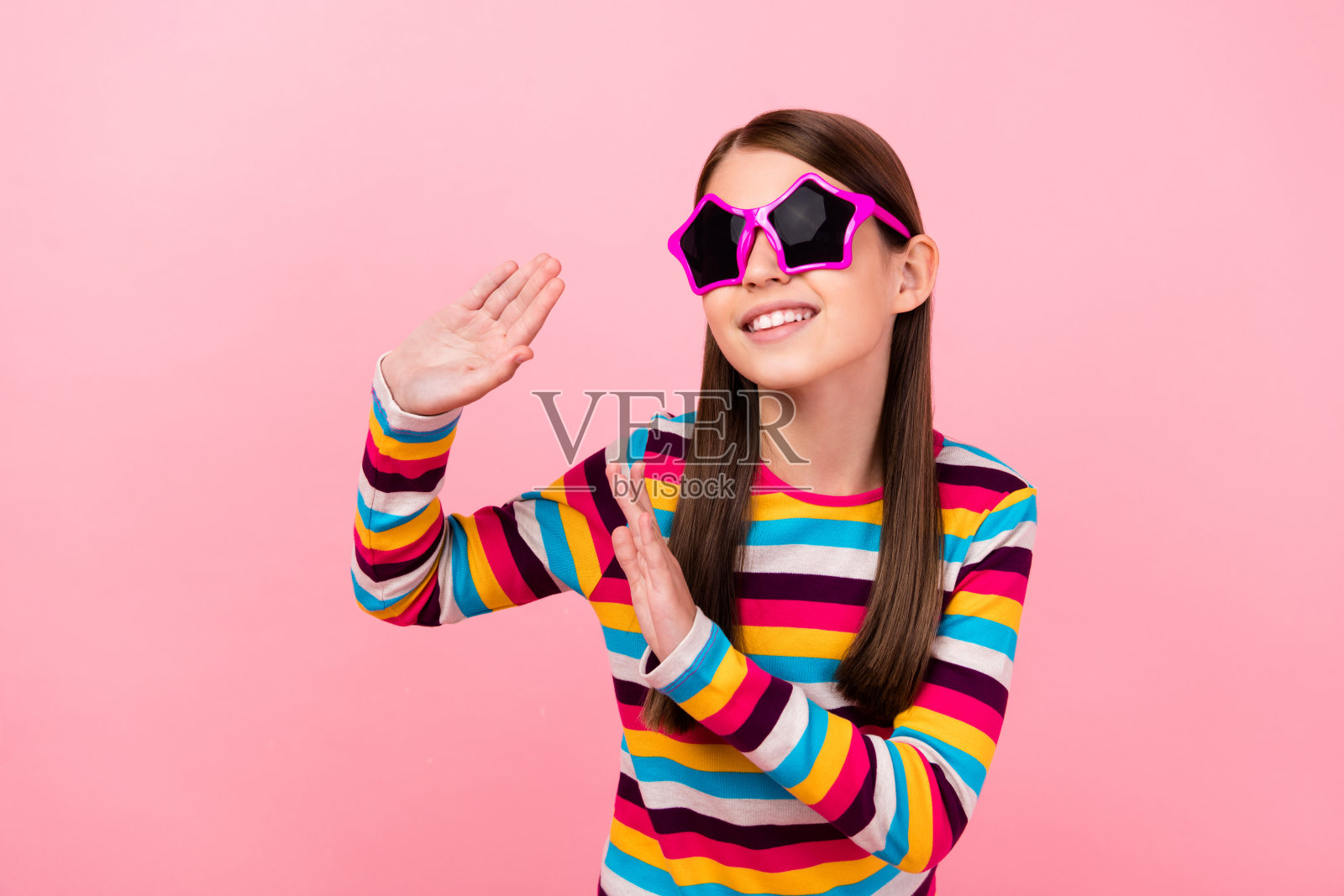 搞笑的小淑女跳舞的照片有无忧无虑的乐趣，戴明星太阳镜，条纹衬衫孤立的粉红色背景照片摄影图片