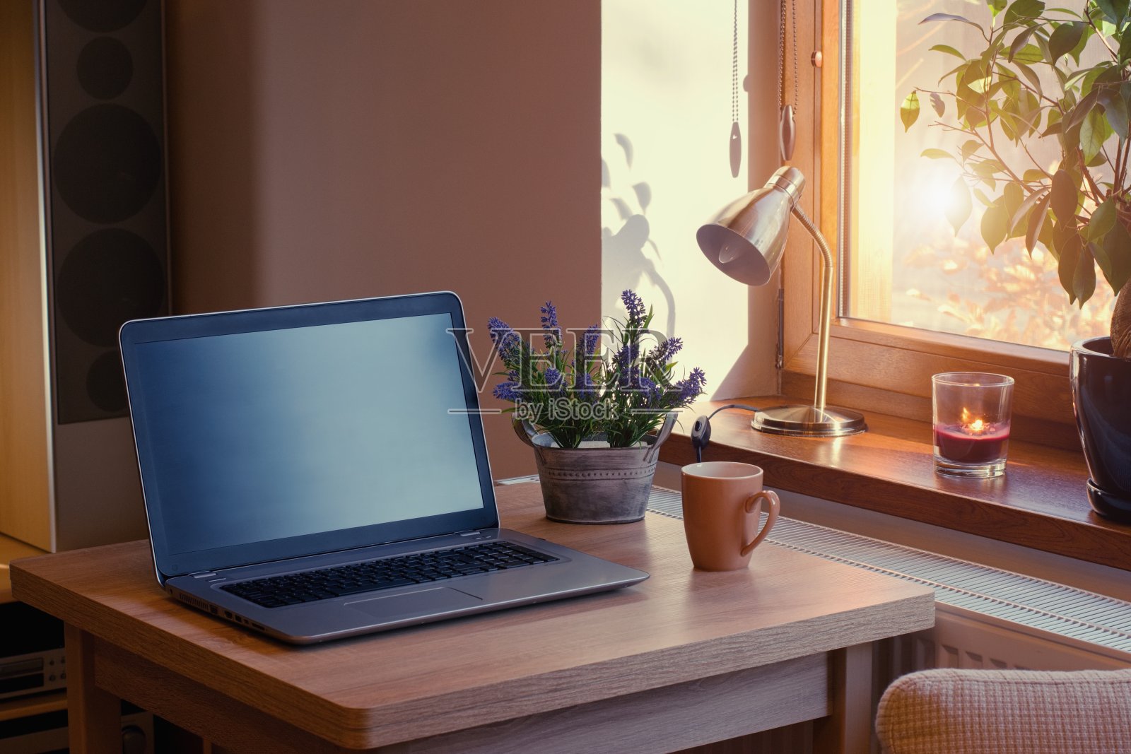 有笔记本电脑的家庭工作场所。舒适的家庭内部在温暖的窗户光线。照片摄影图片