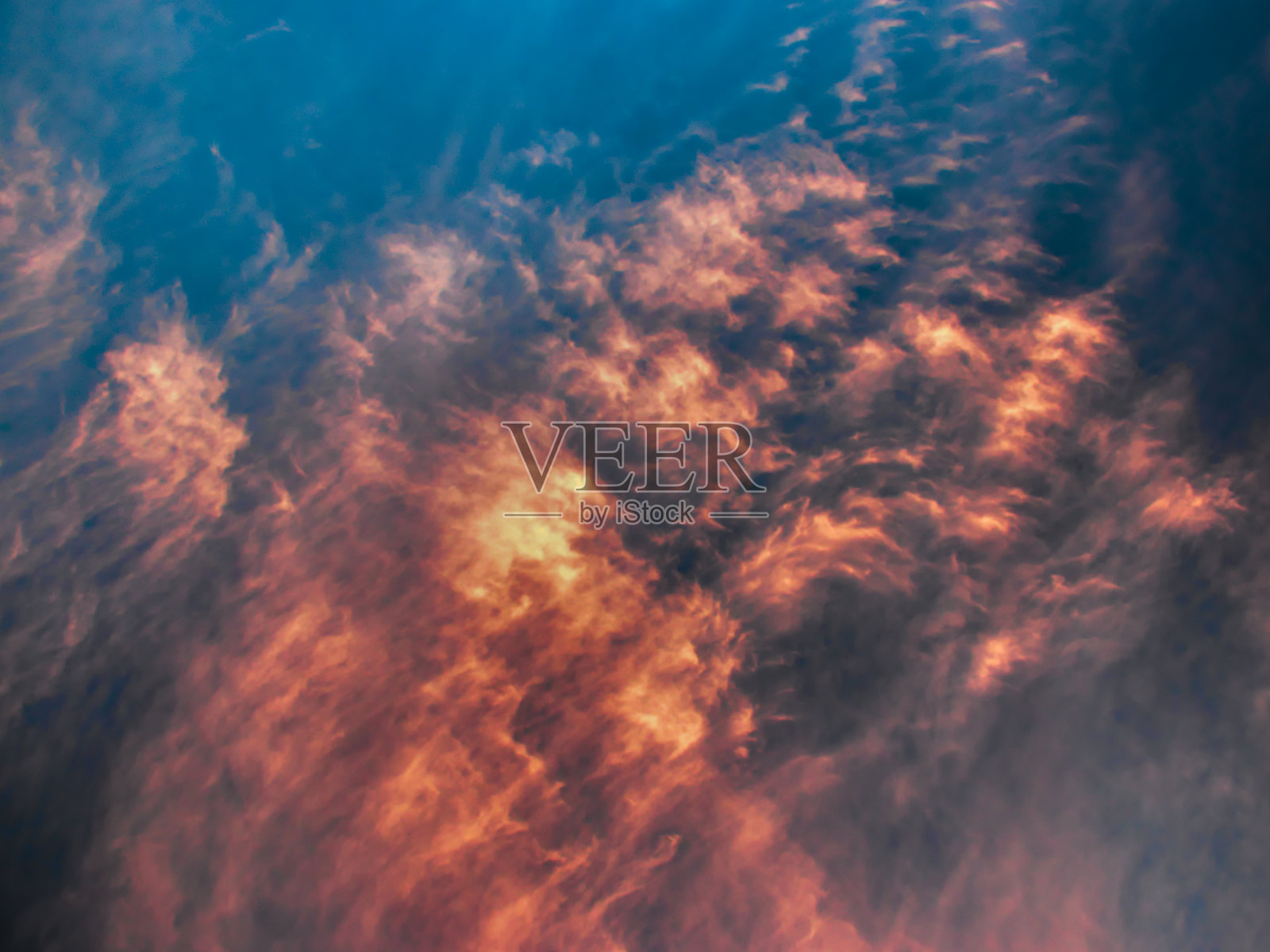 一簇簇金黄色的云被风吹散在朦胧的蓝天上。照片摄影图片