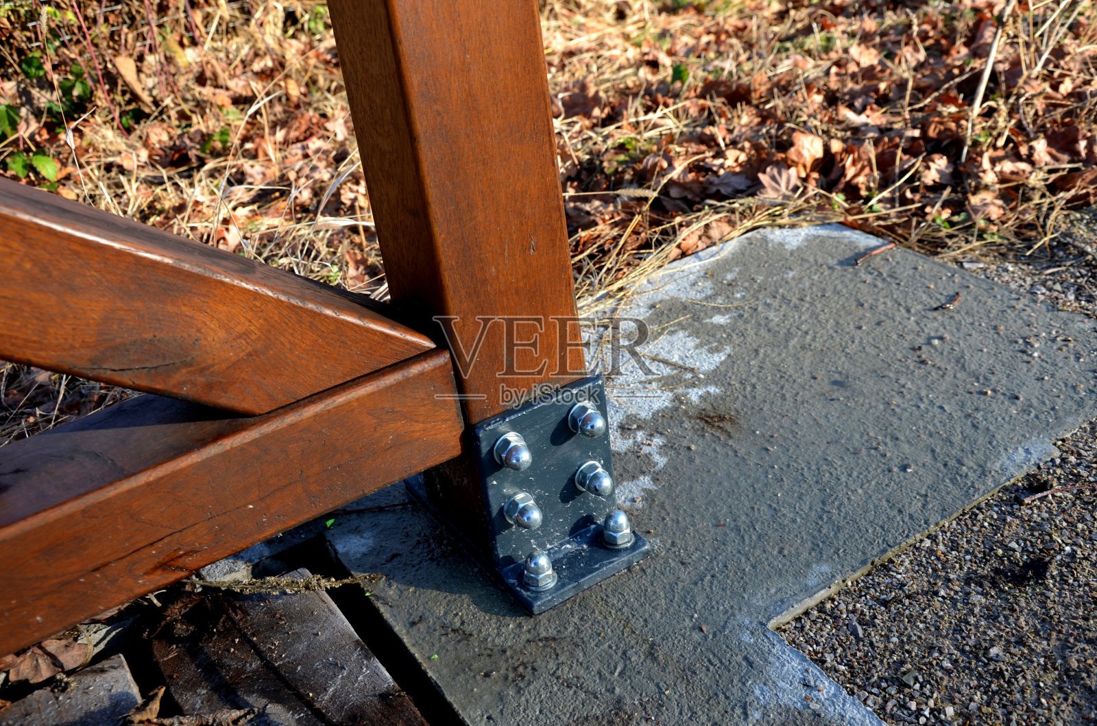 一座有木栏杆的公园桥横跨小溪。这些梁被固定在一根支撑混凝土基础的钢横梁上。路由碎石，桥头前障照片摄影图片