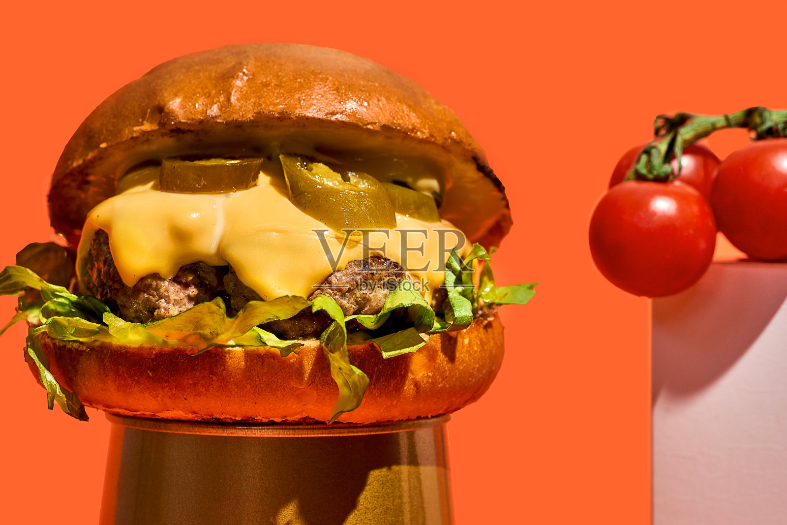 诱人的汉堡与墨西哥胡椒，奶酪和生菜在橙色的背景照片摄影图片