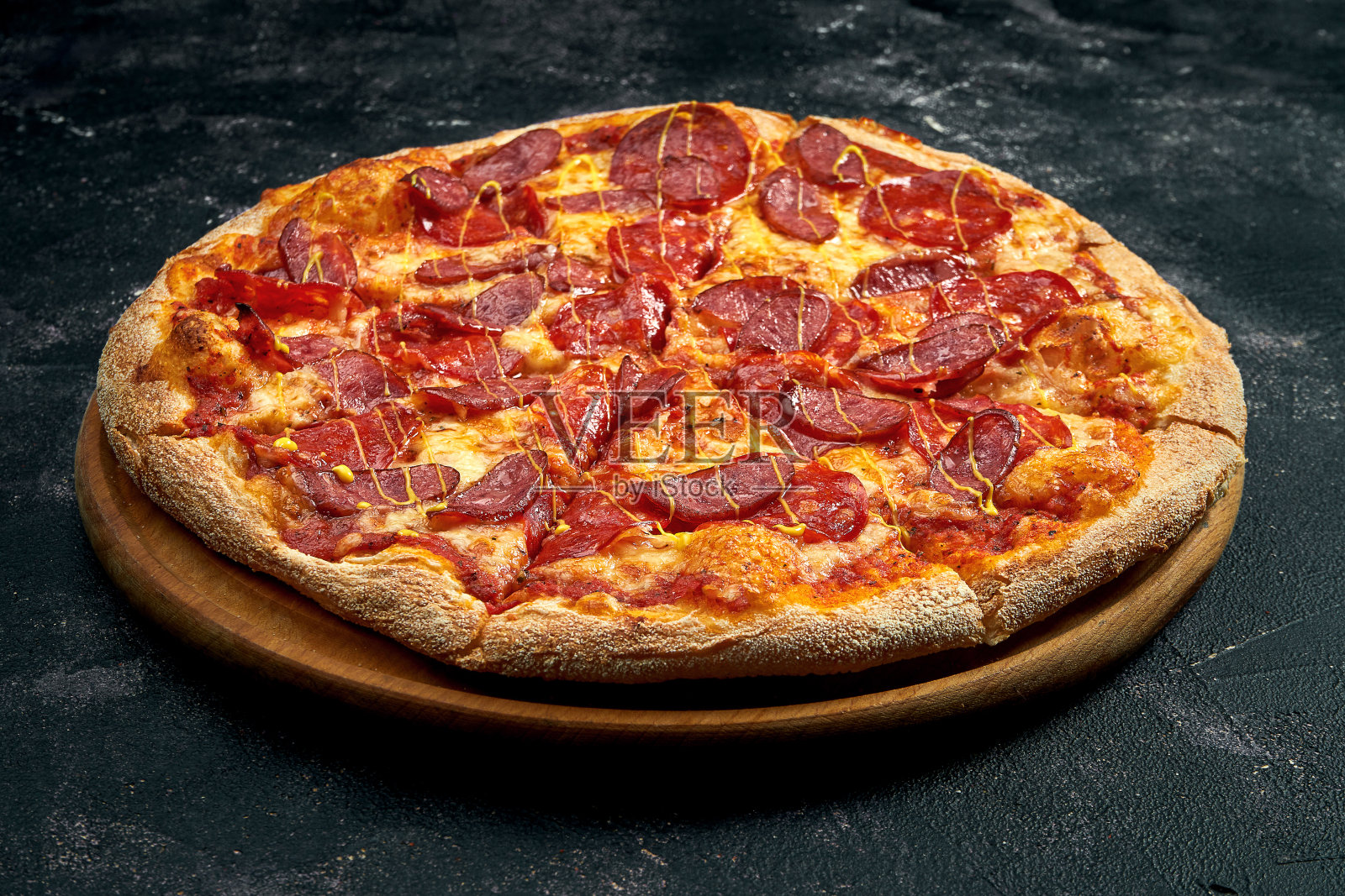 披萨配意大利腊肠和烟熏香肠，背景是黑色的石头。45度视角。特写,有选择性的重点照片摄影图片