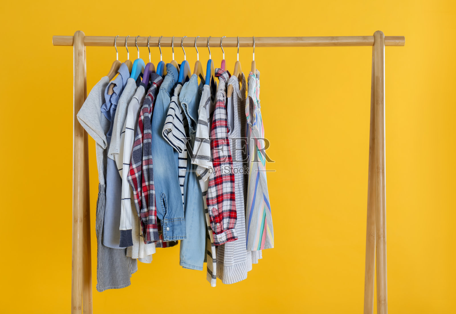 架与时尚的儿童服装在黄色背景照片摄影图片