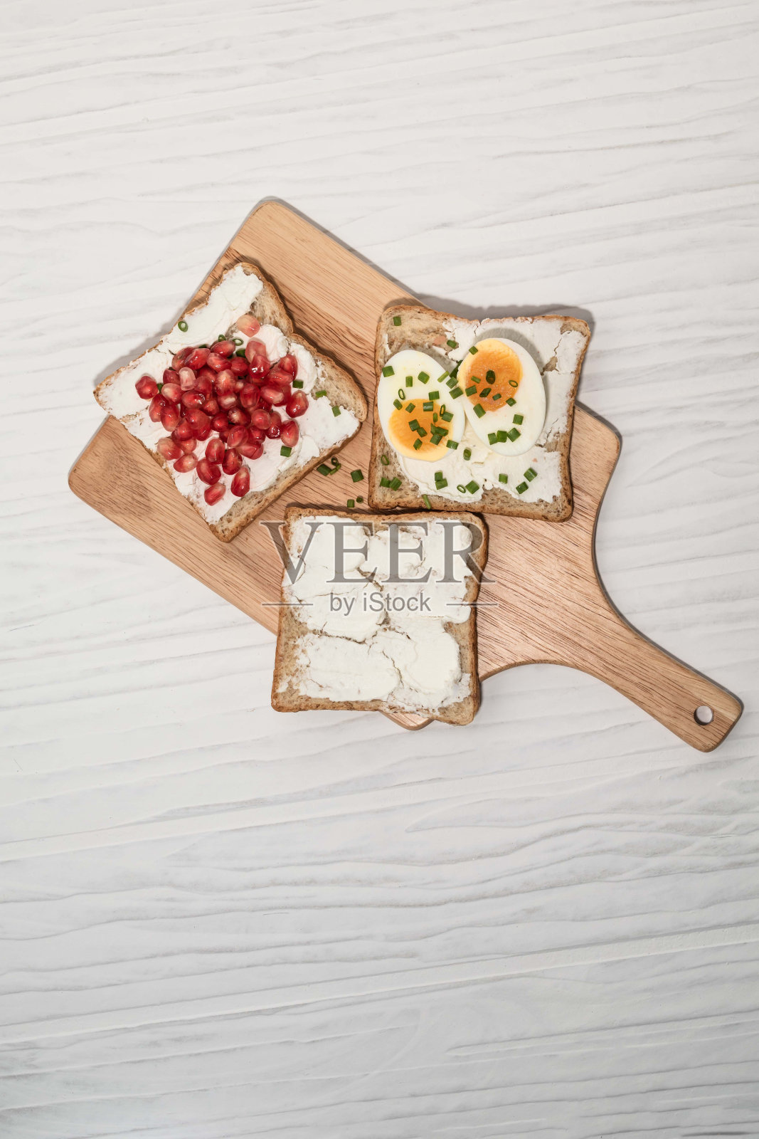 面包有奶油芝士和石榴煮鸡蛋在白色的背景。照片摄影图片