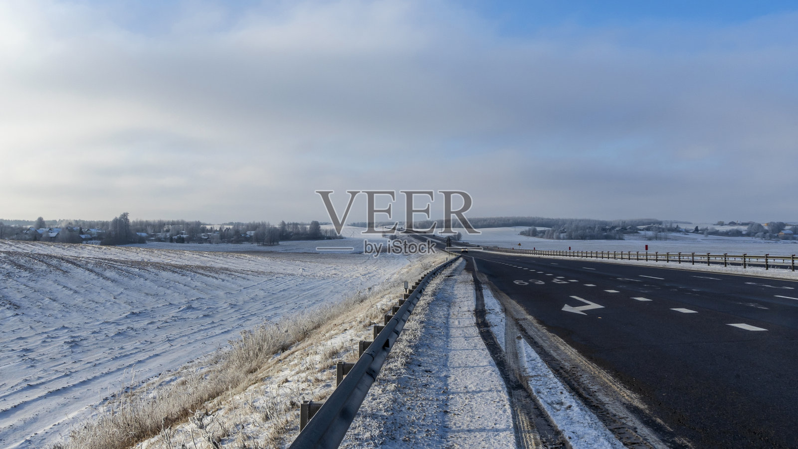 乡村公路穿越冬日田园风光。黑色的干净的沥青。穿过白雪覆盖的田野的冬季道路。照片摄影图片