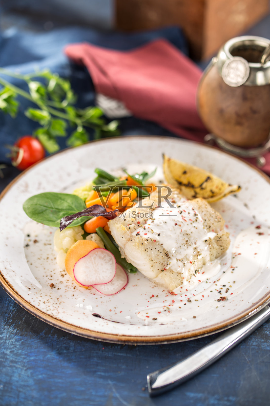 美味健康的鱼片与小胡萝卜，萝卜和柠檬在白色盘子上蓝色的背景照片摄影图片