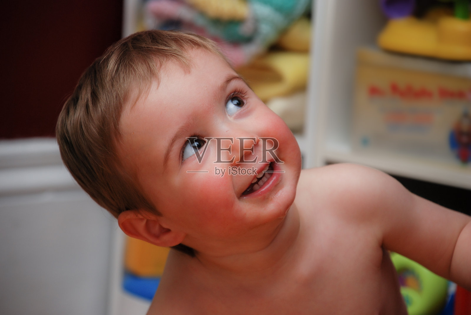 快乐的蹒跚学步的男孩微笑着向上看照片摄影图片