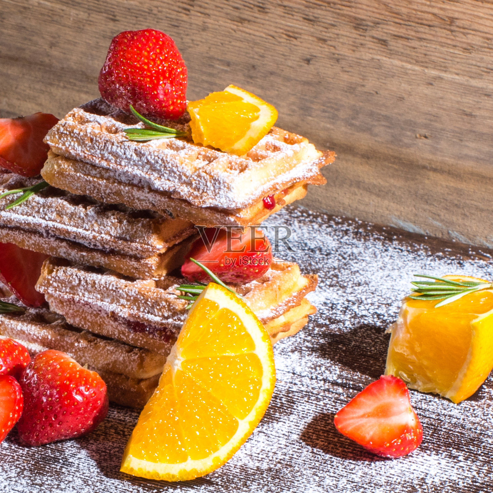 比利时华夫饼配橘子酱和草莓，橘子片，迷迭香，撒上糖粉，放在旧木桌上，侧边看，复印空间，健康早餐照片摄影图片
