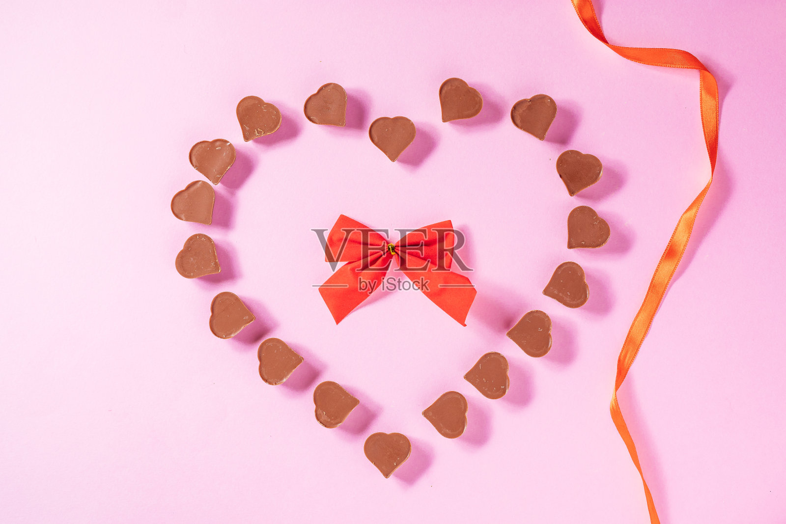 粉色背景红色丝带心形巧克力，情人节概念照片摄影图片