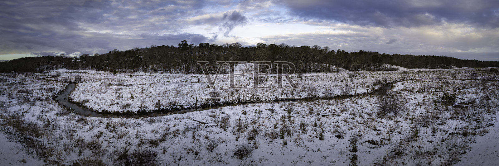 荒野平原上的雪，蜿蜒的河流像蛇一样流淌。1月，马萨诸塞州科德角冬季森林山顶的壮观云景。照片摄影图片
