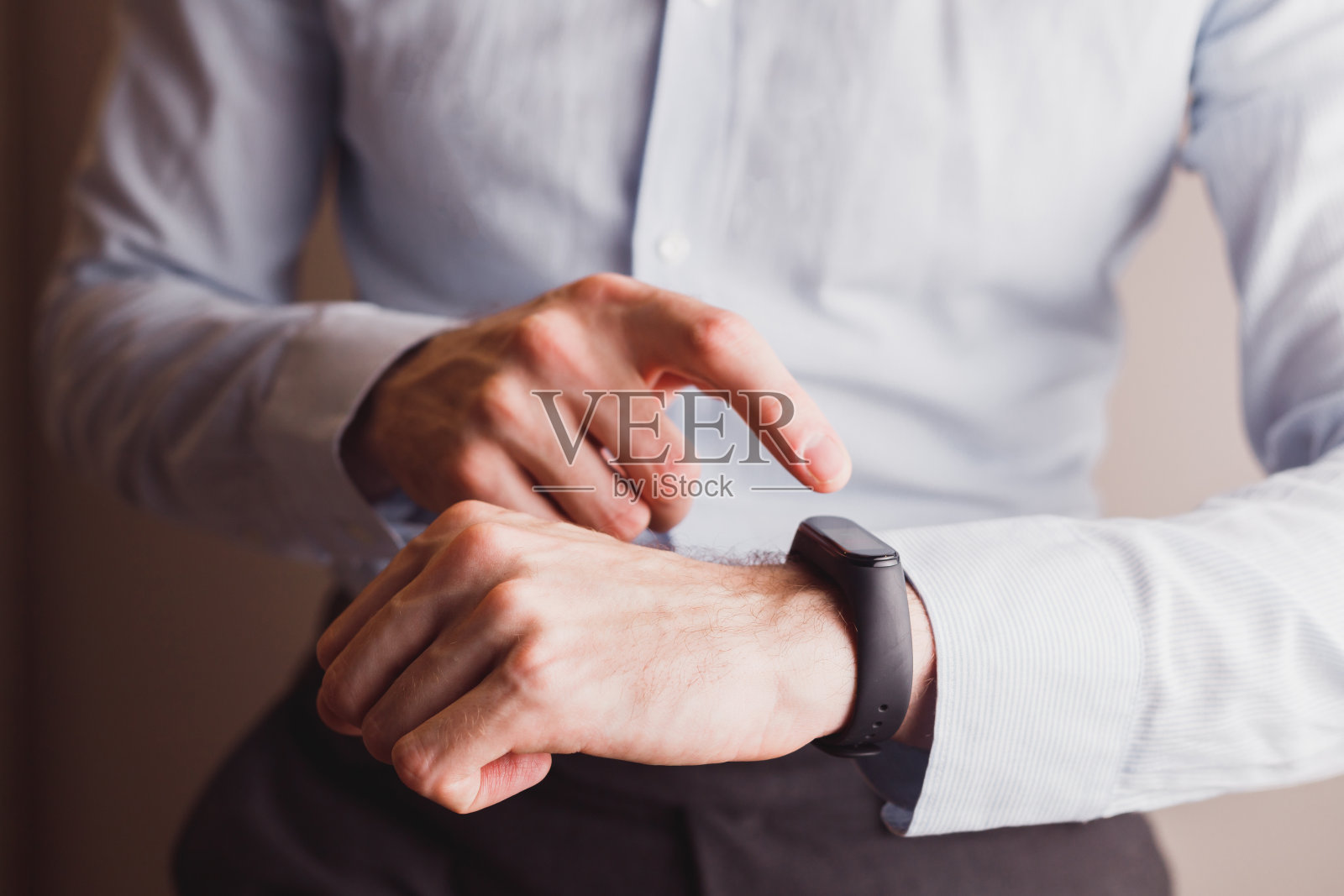 穿蓝色衬衫，戴智能手表或手镯的上班族。科技的生活方式照片摄影图片