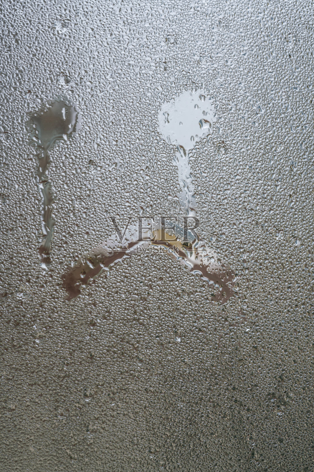 用手在玻璃上画出伤心不开心的脸形状，像在哭照片摄影图片