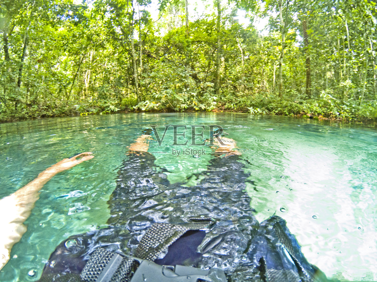 在巴西马托格罗索州的诺布雷斯，一名男子漂浮在森林里的蓝色绿松石湖上照片摄影图片