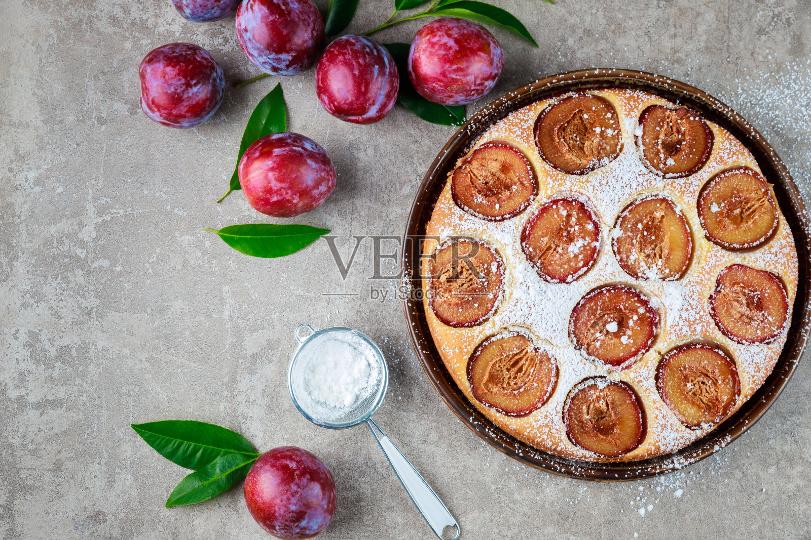 鲜红李子和绿叶的馅饼。照片摄影图片