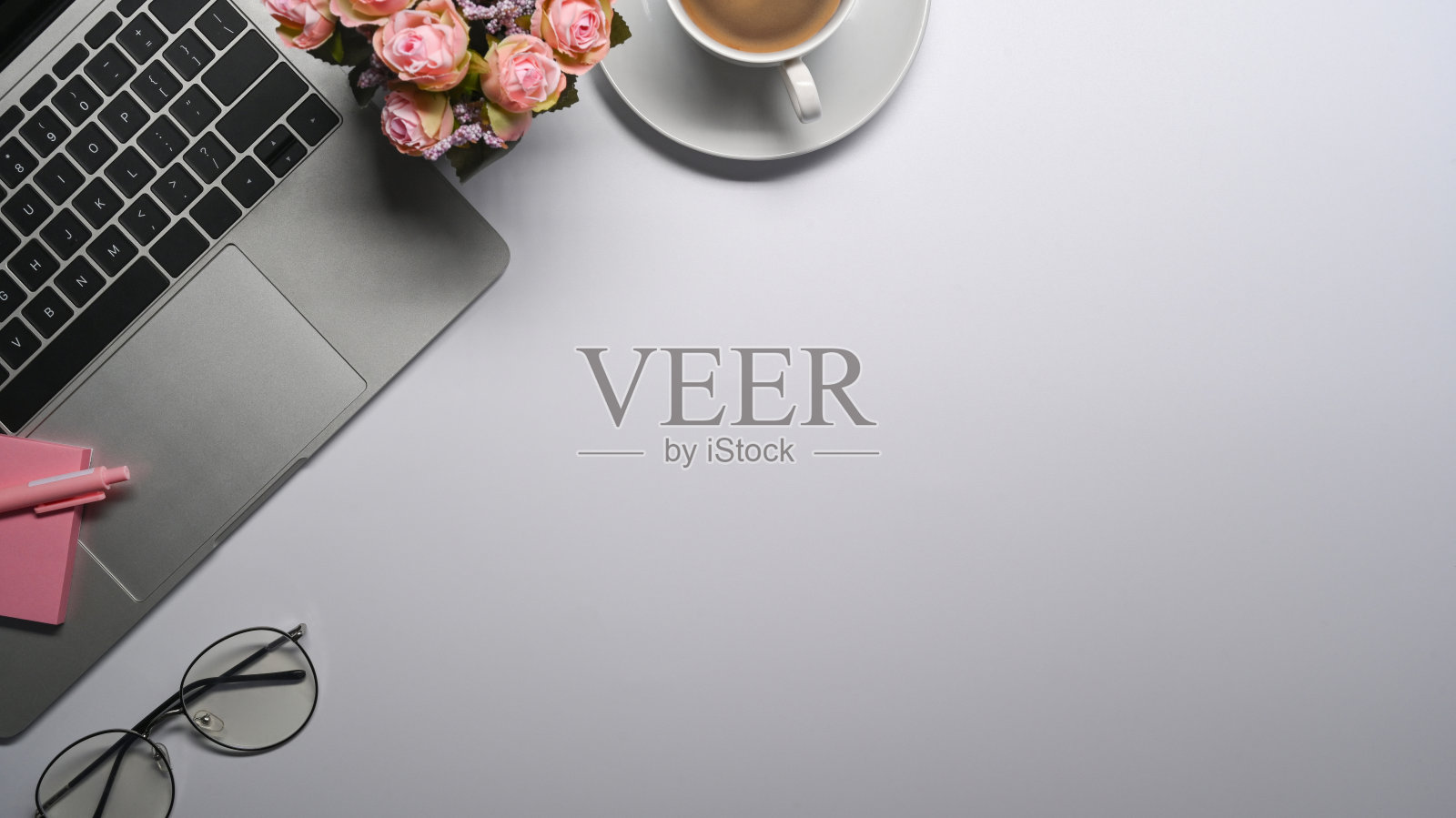 白色办公桌，配有笔记本电脑、眼镜、咖啡杯和便利贴。照片摄影图片