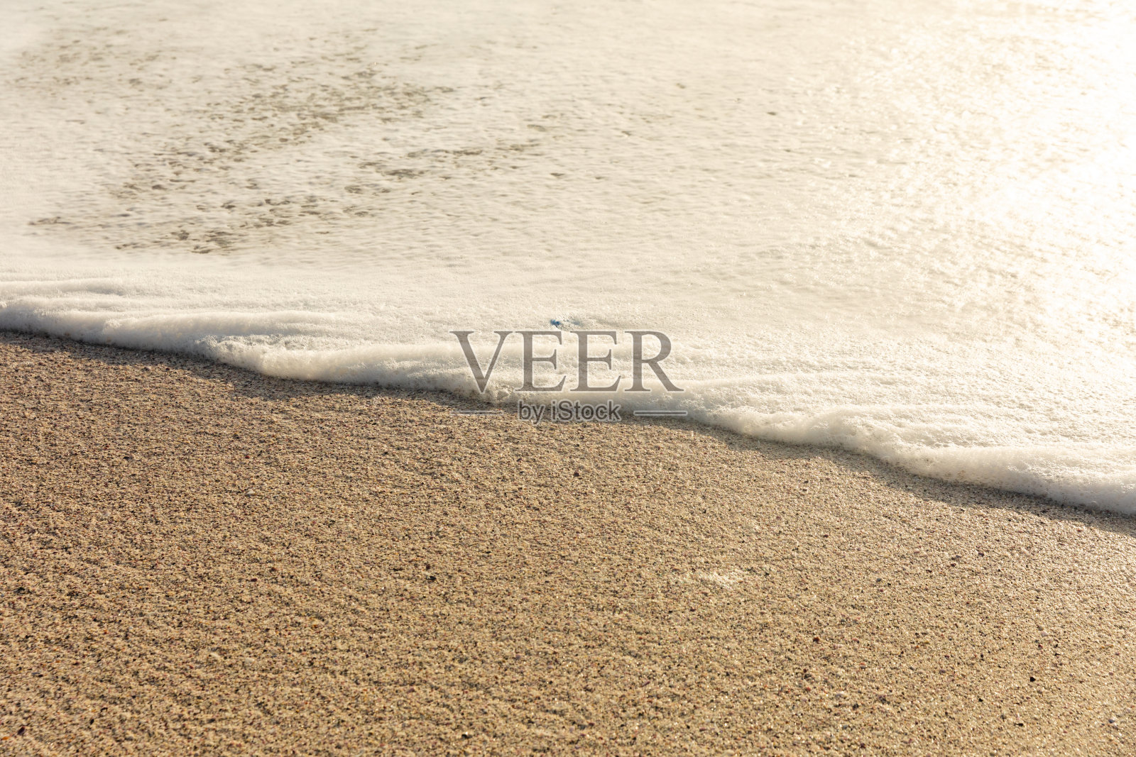 在阳光明媚的海滩上，白色海浪泡沫的高角度视图照片摄影图片