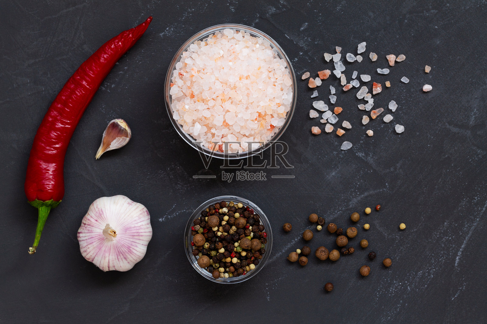 红色的辣椒，新鲜的大蒜，粉色的喜马拉雅盐和混合的辣椒在玻璃碗的黑色背景。俯视图复制空间。一套用于烹饪的各种香料。照片摄影图片