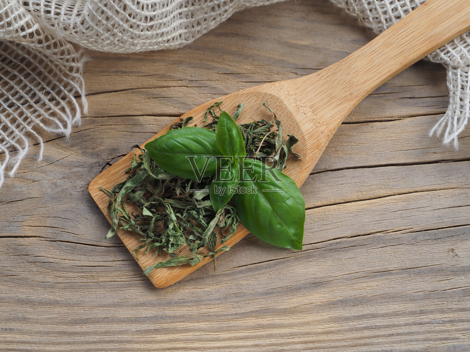 干罗勒和绿罗勒叶放在木勺里，木桌上，餐巾，平放。麻辣香草罗勒具有营养和烹调作用照片摄影图片