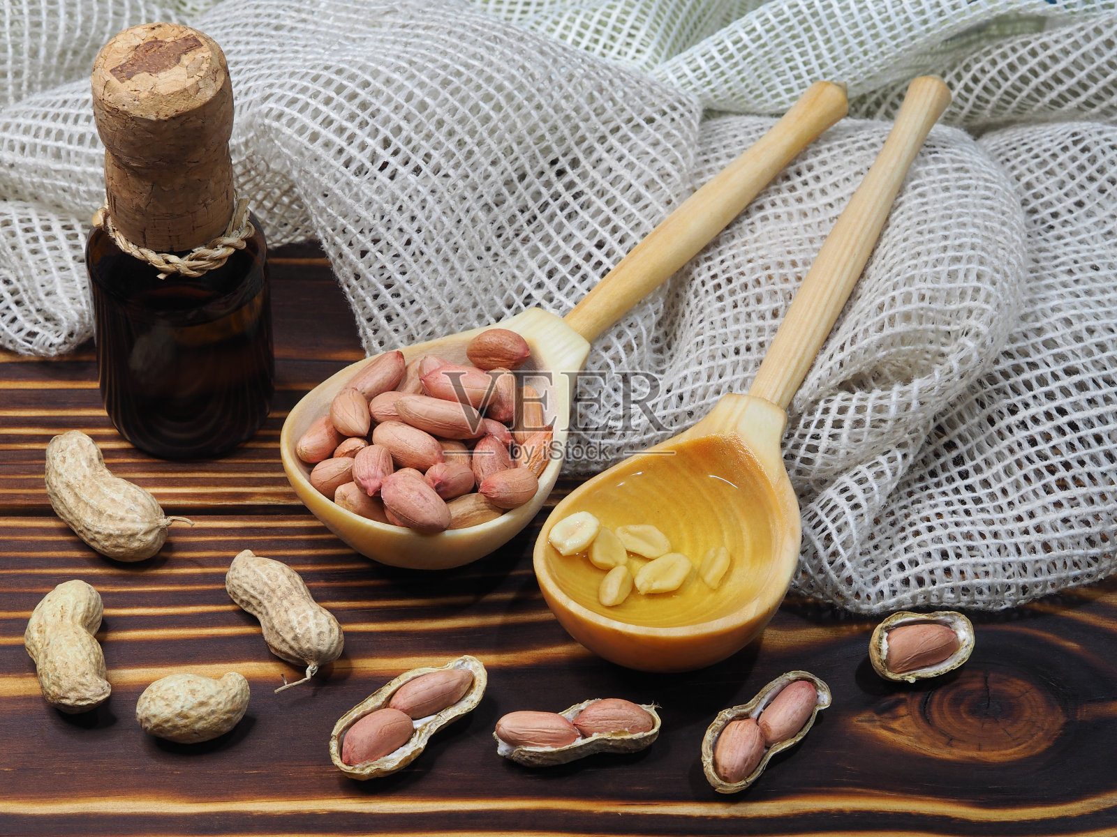 去皮花生，在壳坚果，花生油在一个瓶子和一个木勺在木制背景，特写，俯视图。天然花生仁为健康饮食照片摄影图片