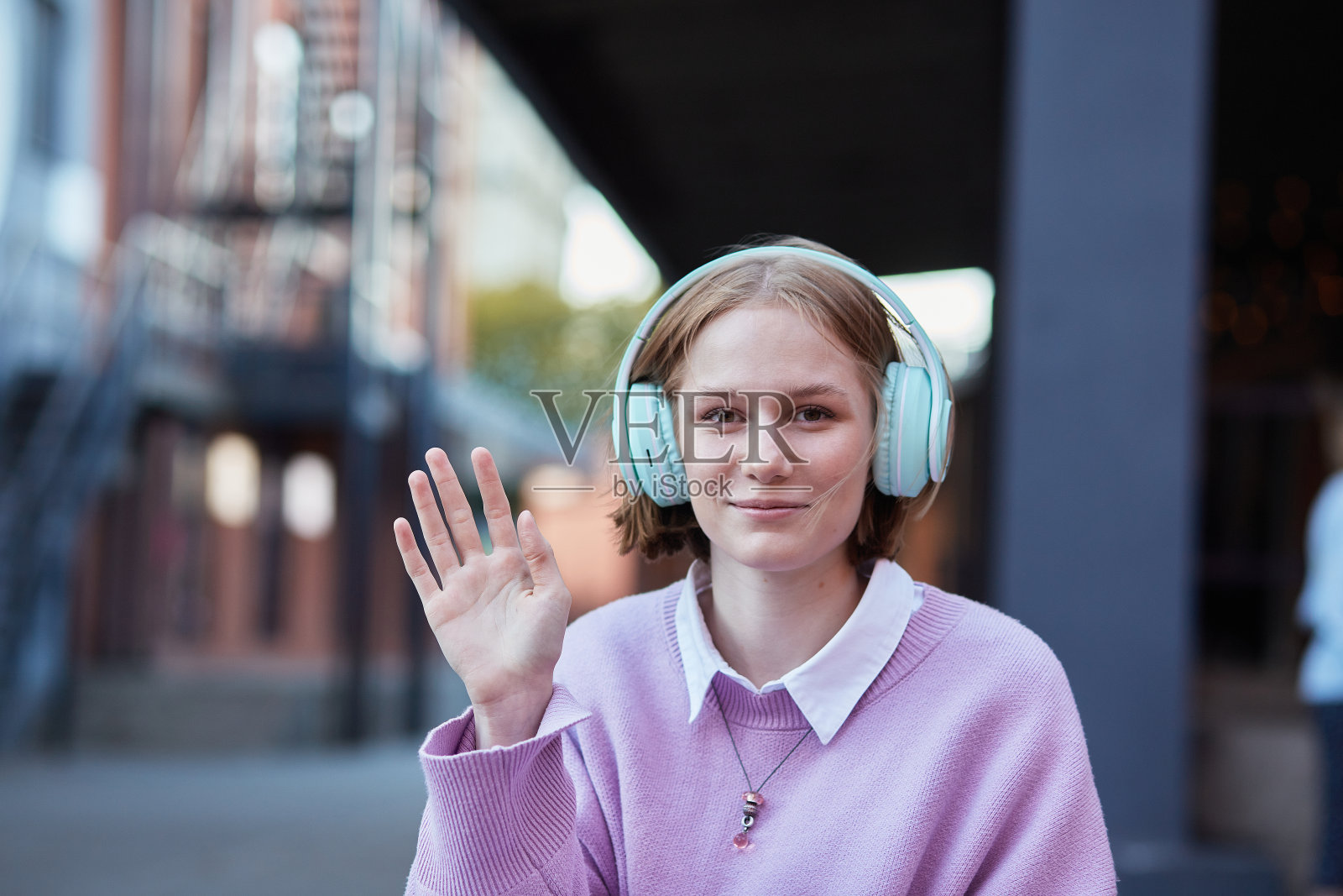 快乐的女人看着网络摄像头挥手致意。照片摄影图片