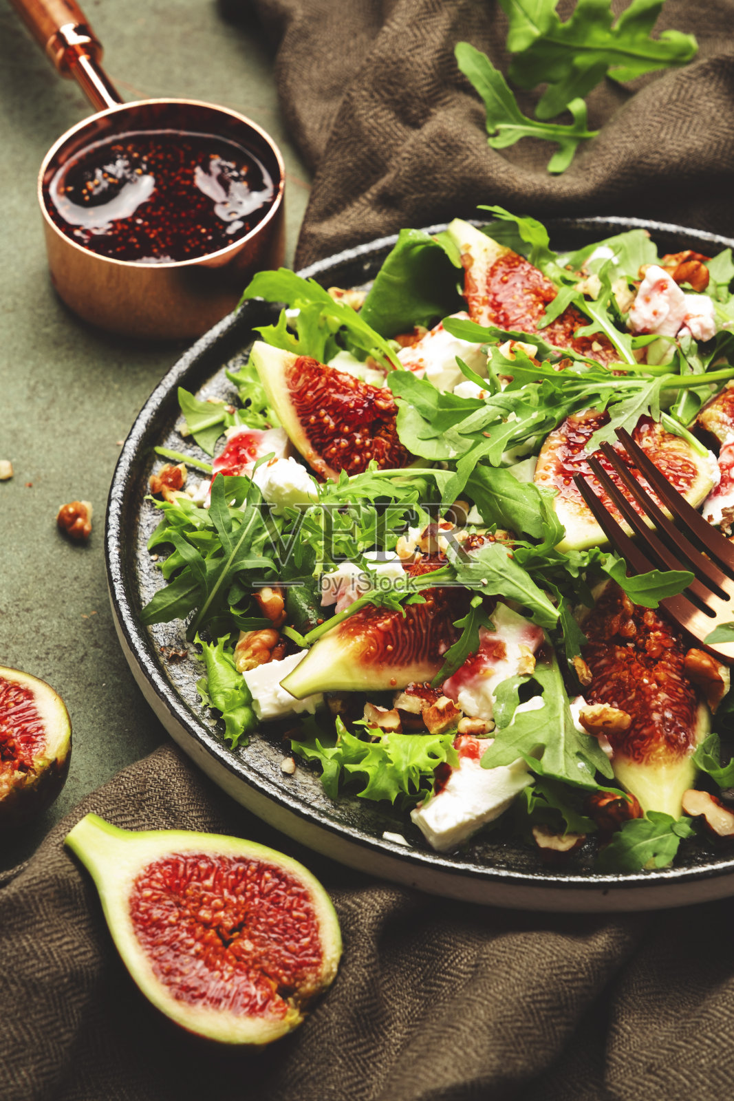 美味的无花果沙拉与山羊奶酪，坚果，芝麻菜和果酱酱在生锈的绿色桌子背景，俯视图，复制空间照片摄影图片