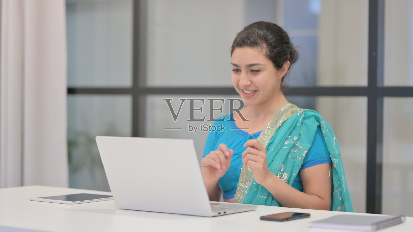 印度妇女在办公室用笔记本电脑进行视频通话照片摄影图片