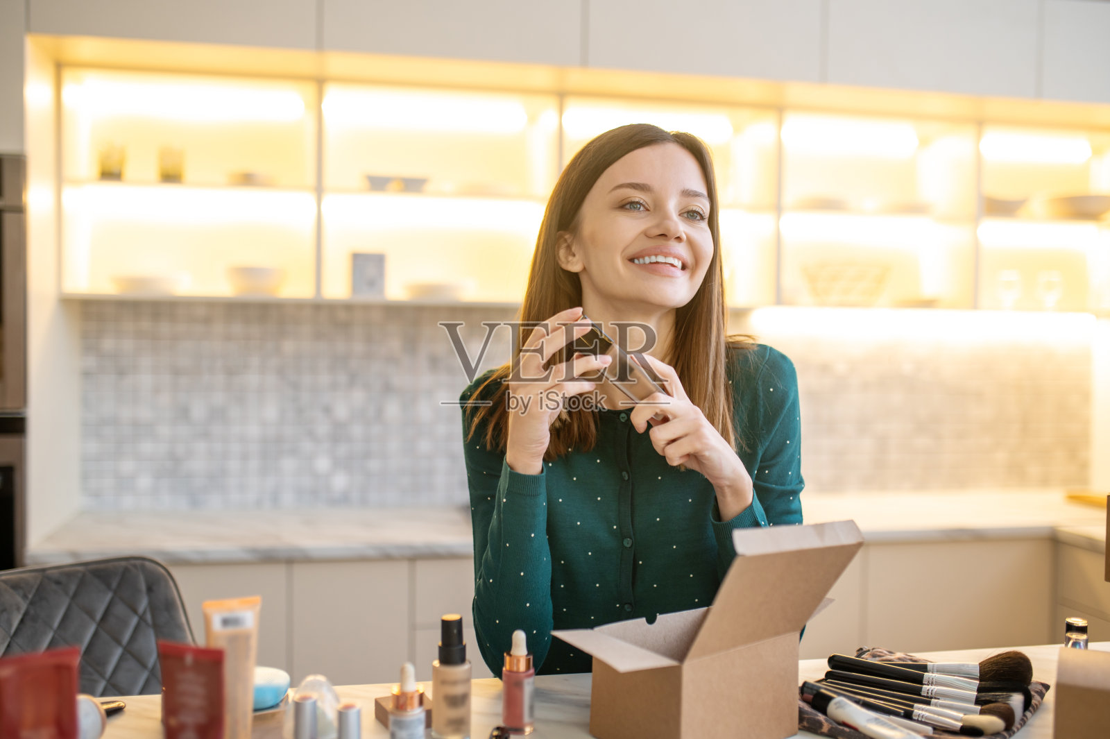 年轻的女人穿着绿色的衣服，代表着新的化妆品，看起来很满足照片摄影图片