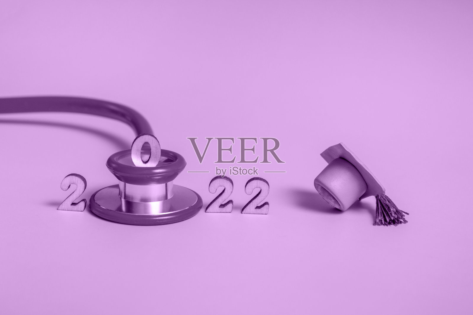 毕业帽与听诊器和数字2022紫色背景，特写与复制空间。医学教育的概念。照片摄影图片