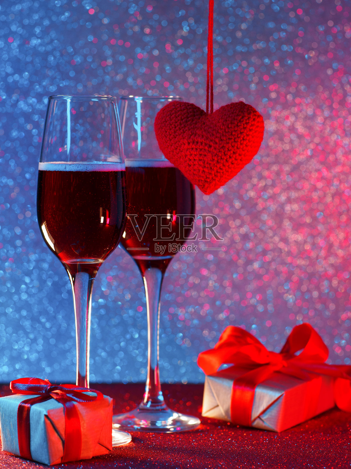 祝你情人节快乐。两杯起泡酒，霓虹灯散景背景，礼品盒和一颗红心照片摄影图片