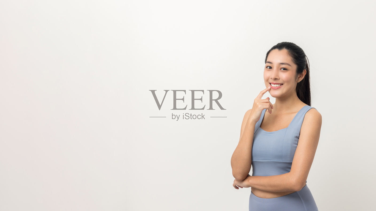 快乐年轻美丽的亚洲妇女与运动服装在孤立的白色背景。人像运动妇女站姿势锻炼锻炼在工作室。照片摄影图片