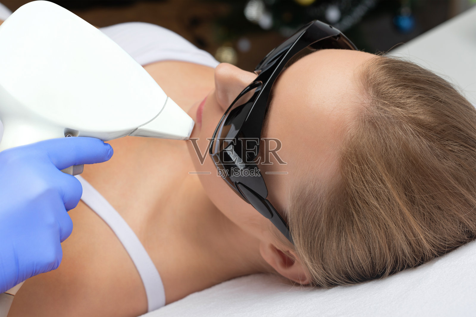 一个女人脸上的脱毛手术。在美容院做激光美容的美容师。面部皮肤护理。硬件ipl美容照片摄影图片
