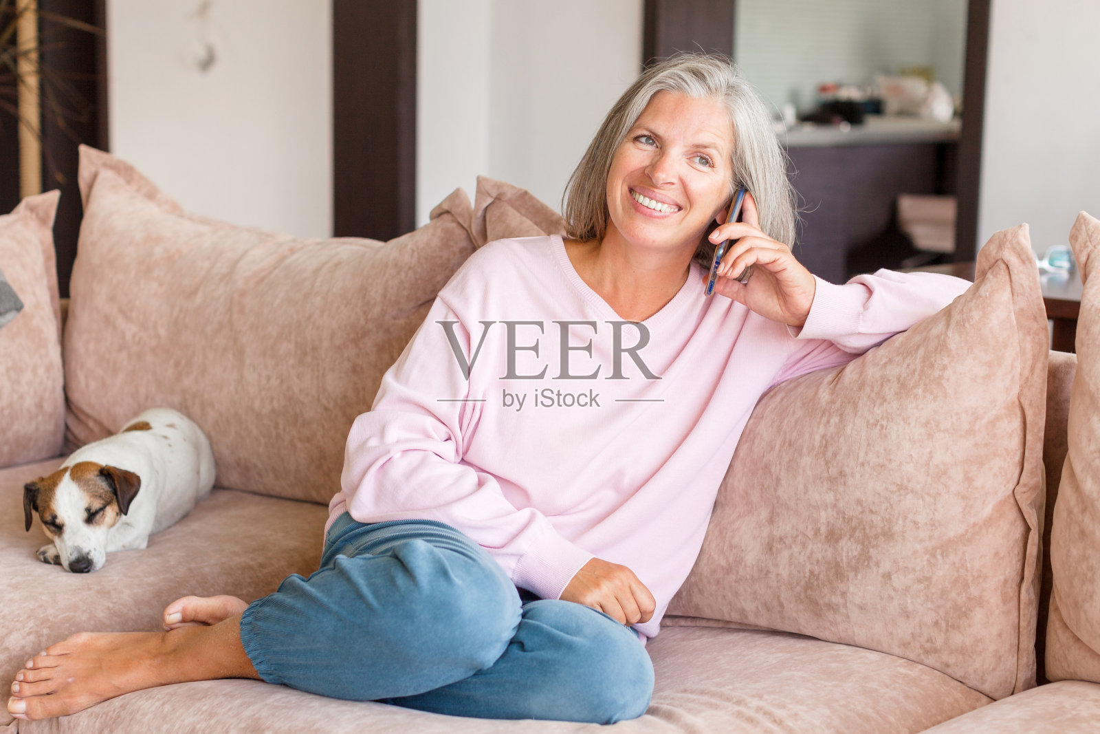 愉快的中年白人妇女在沙发上用手机聊天照片摄影图片