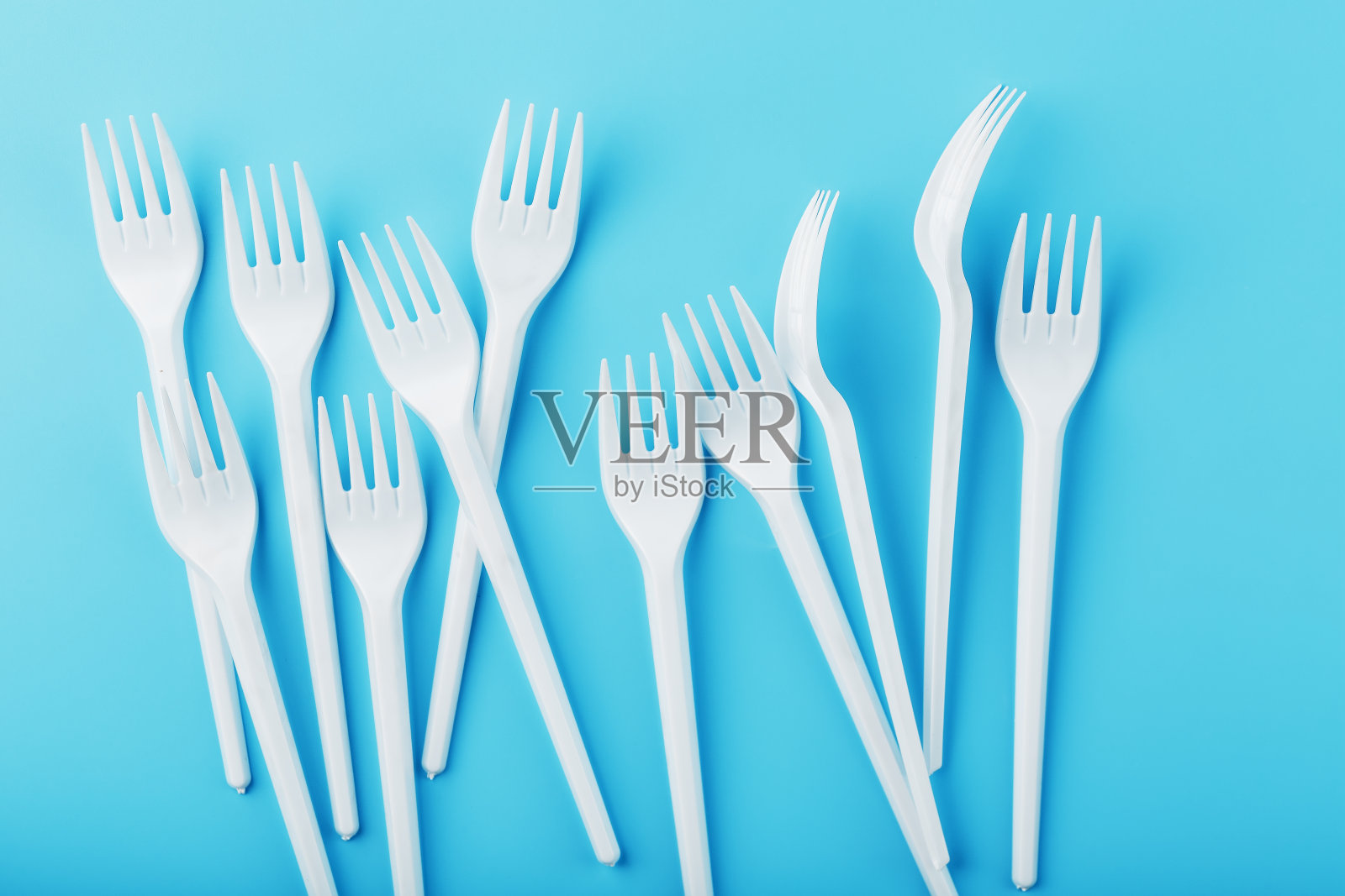 白色塑料叉一次性餐具上的蓝色背景。照片摄影图片