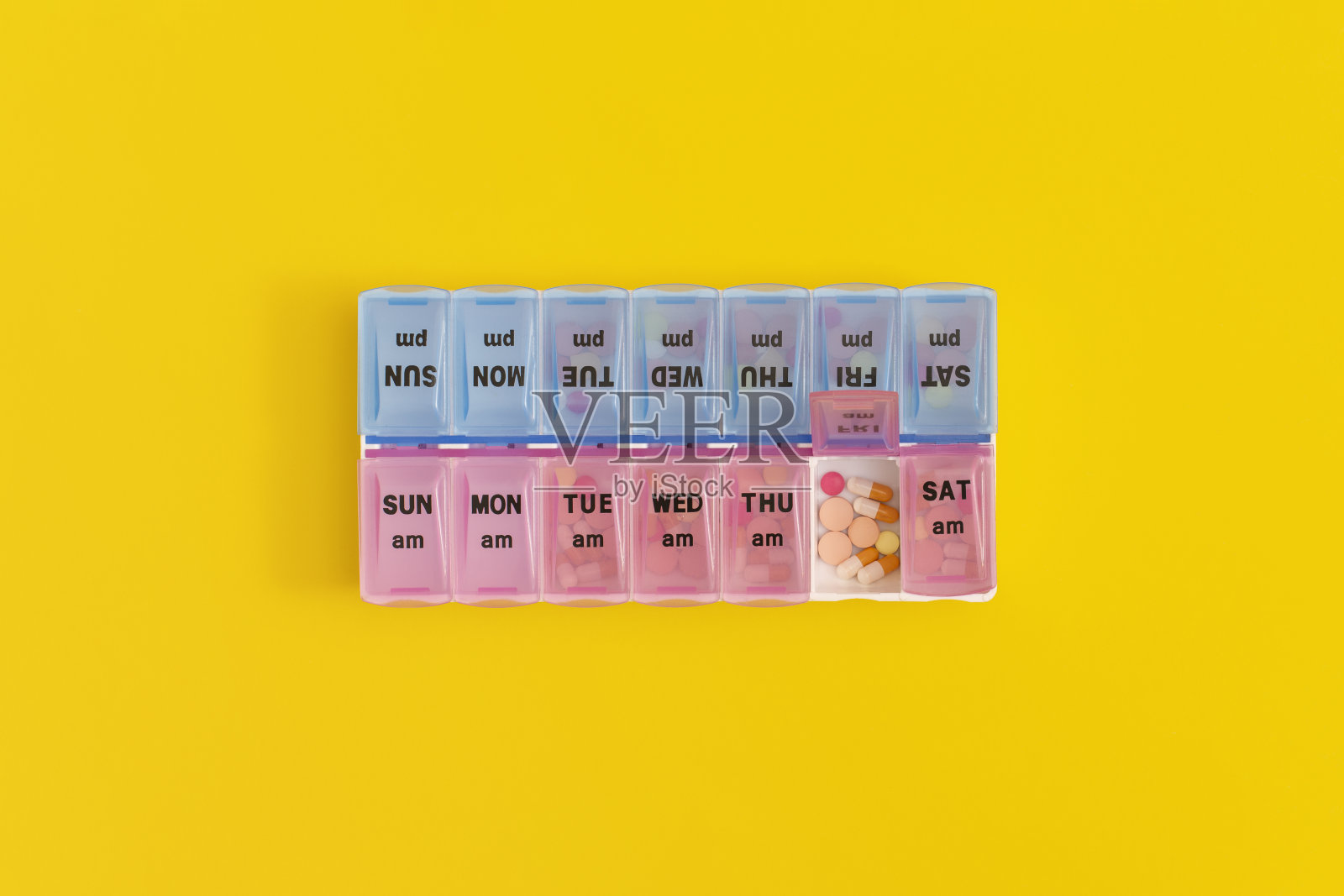 黄色背景上的日常药盒。照片摄影图片
