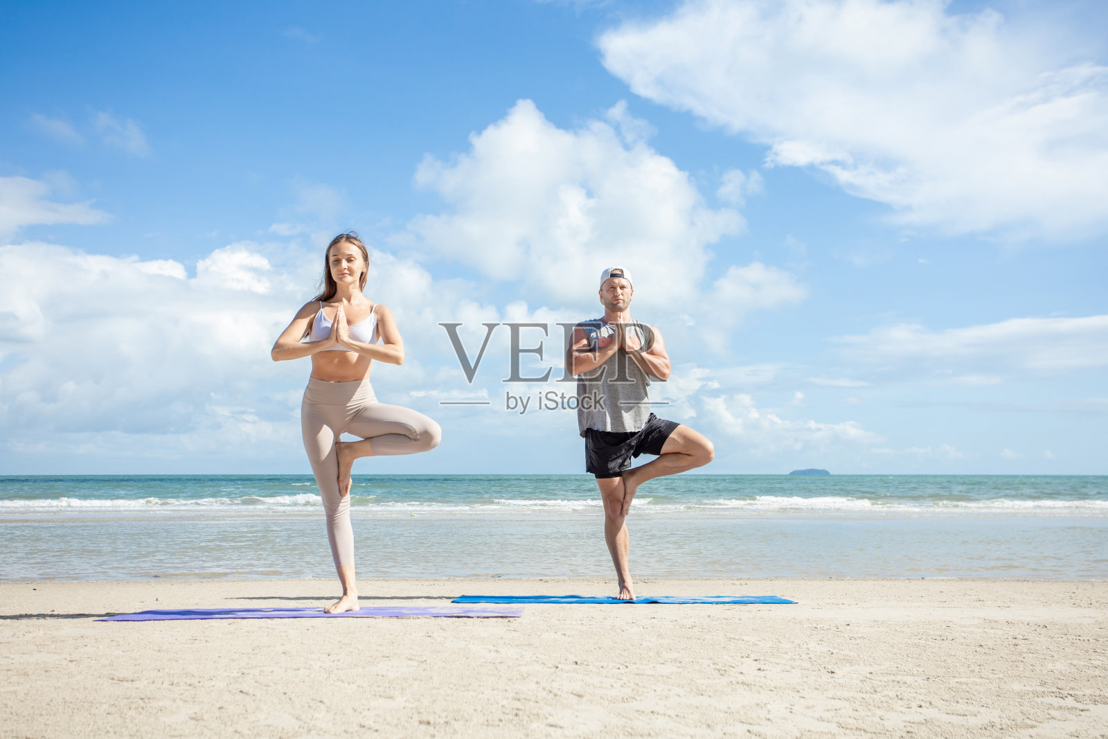 健身、运动和生活方式的概念——情侣在沙滩上做瑜伽练习，男人和女人在沙滩上做瑜伽练习。照片摄影图片
