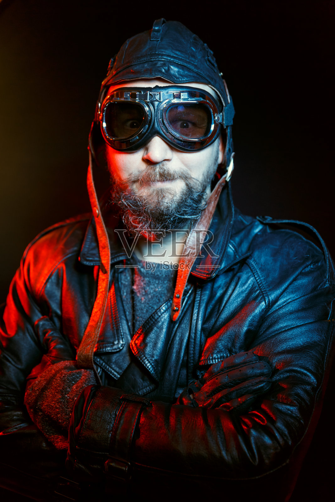 留着胡子的复古司机的肖像，戴着黑色背景的复古眼镜和皮革头盔。照片摄影图片