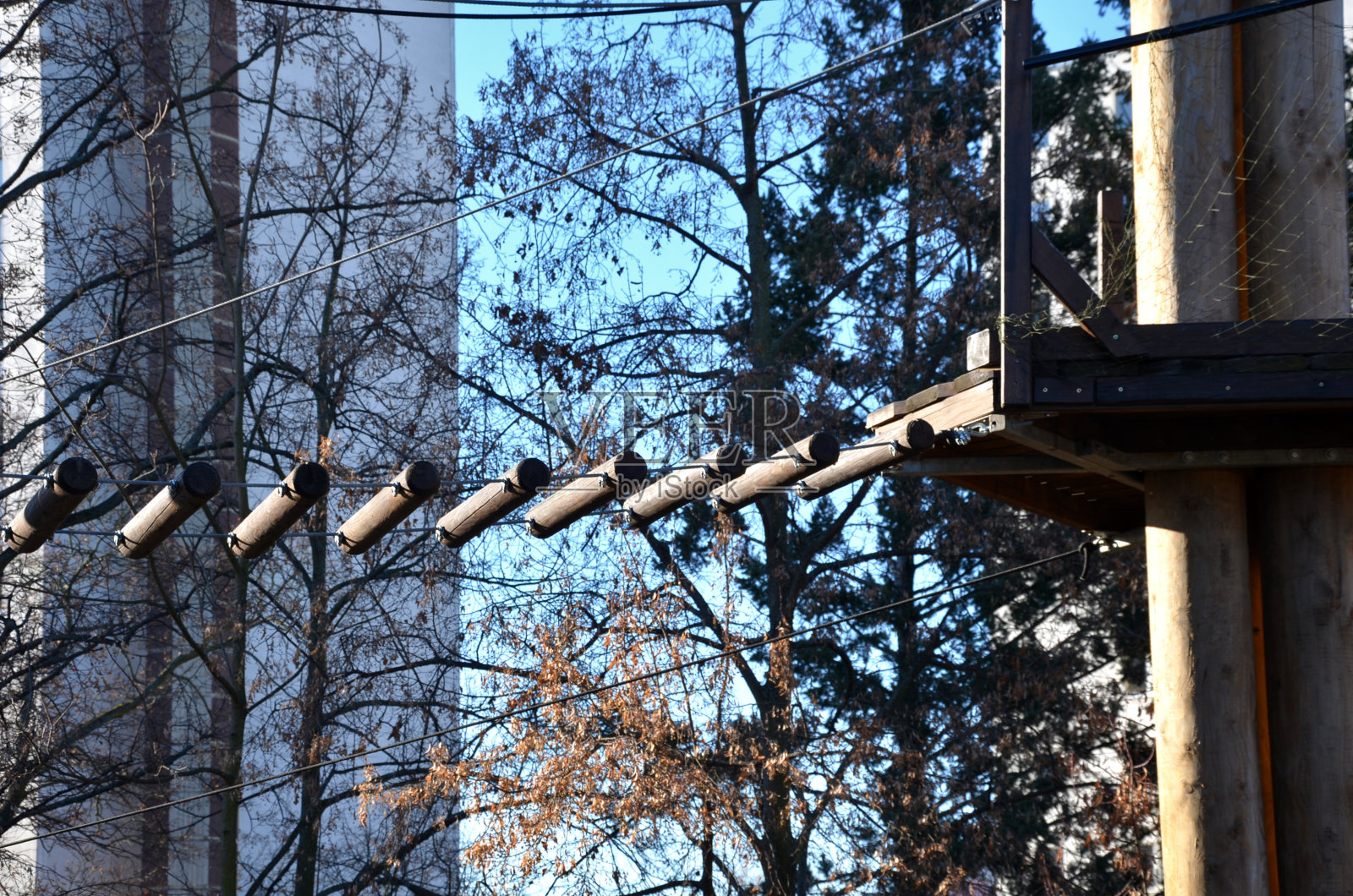 攀爬中心、树顶之间的绳索障碍场或从杆子上伸出的绳索和离地面很高的绳梯。用攀爬装置和锁扣保护跌倒。肾上腺素照片摄影图片