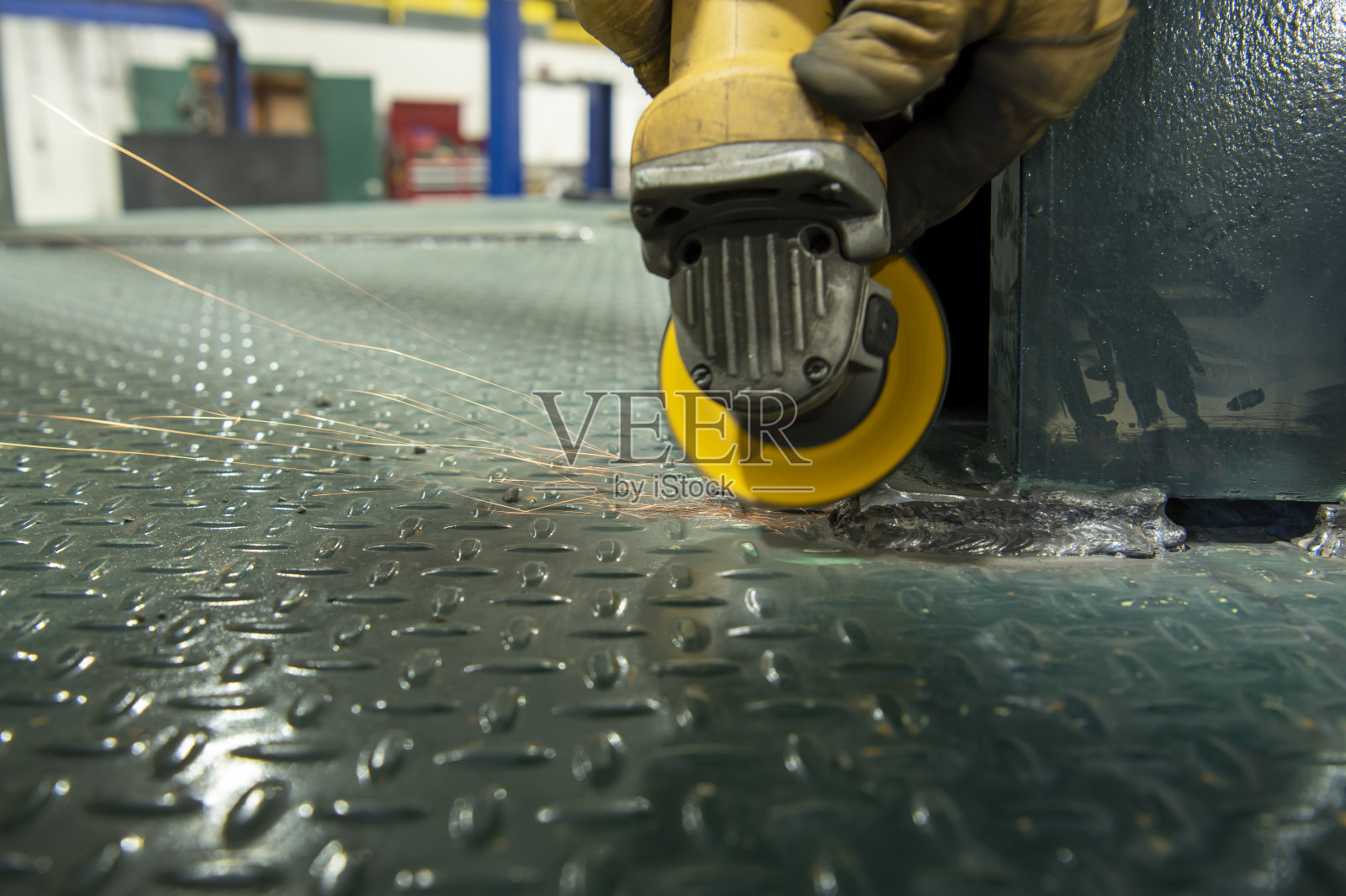 工人使用角磨机清理卡车上的焊缝时，产生的火花产生的光痕照片摄影图片
