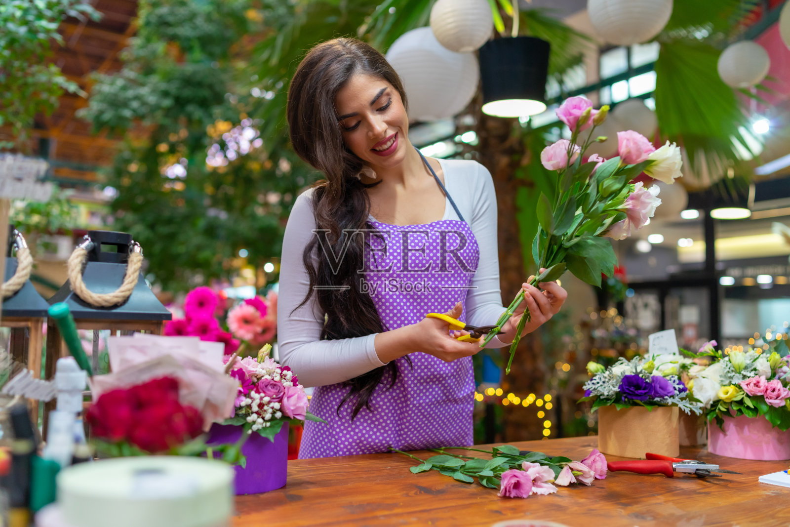 美丽的花商站在花店的柜台后面，用花园剪刀做一束花照片摄影图片