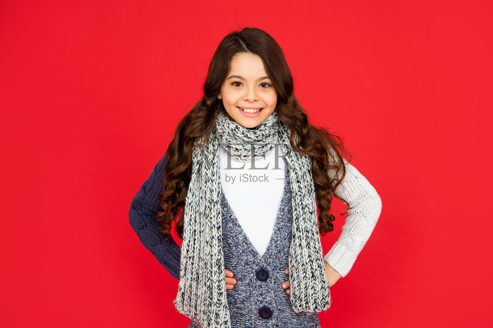 红色背景的少女。穿着暖和衣服的孩子的肖像。表达积极情绪。照片摄影图片