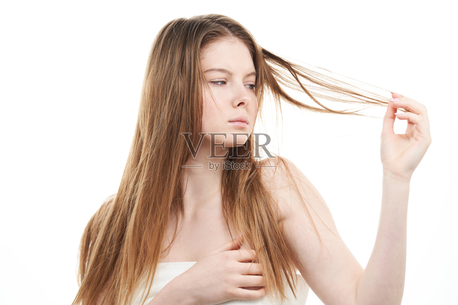 年轻的女人抓着她的头发，看起来很不高兴。照片摄影图片