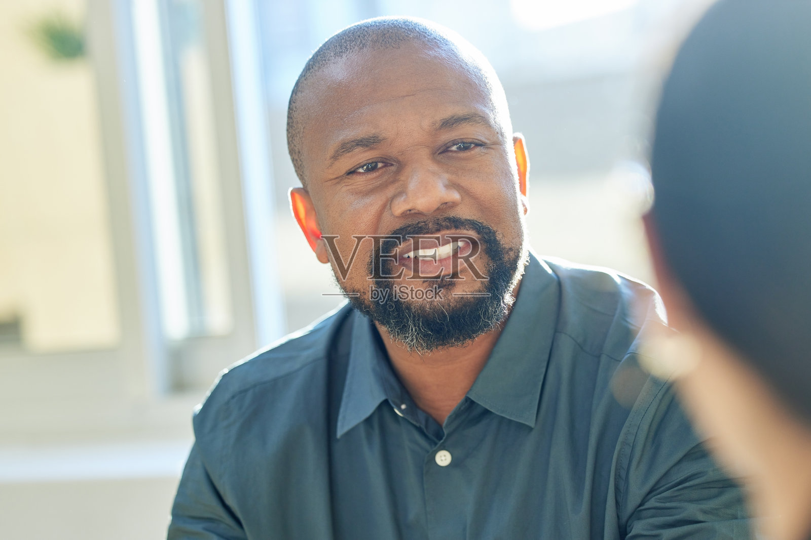 剪裁的镜头，一个英俊的成熟的商人聊天与同事在会议期间照片摄影图片