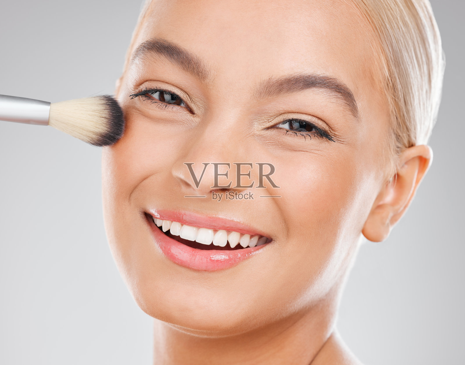 一个迷人的年轻女子在工作室背景下使用化妆刷的照片照片摄影图片