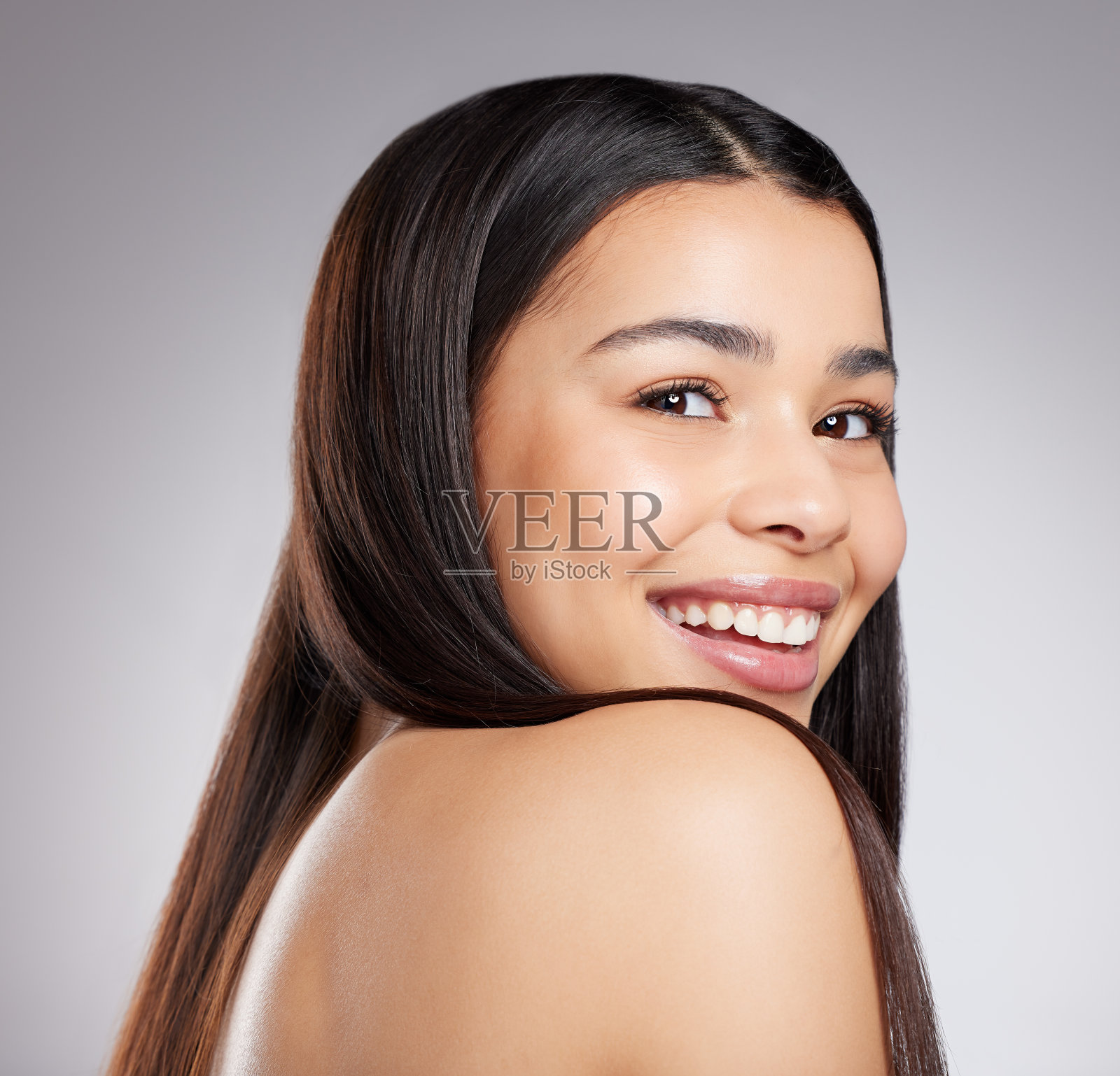 一个迷人的年轻女子在灰色背景下摆姿势的工作室肖像照片摄影图片