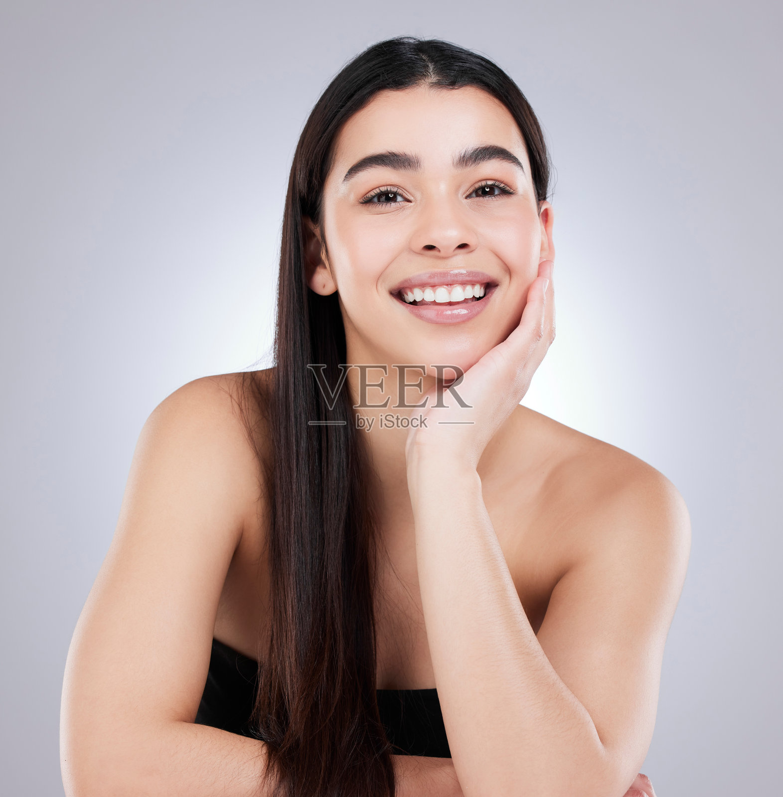 一个迷人的年轻女子在灰色背景下摆姿势的工作室肖像照片摄影图片